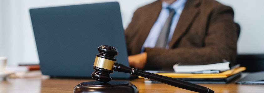 Judges gavel with man typing on laptop