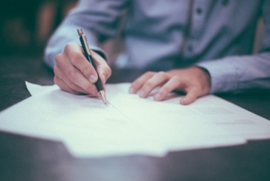 man writing on document