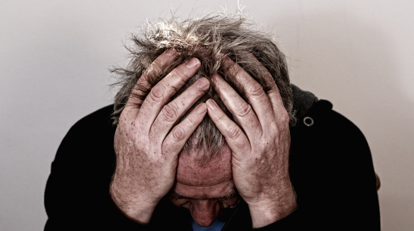 Older man holding head in hands