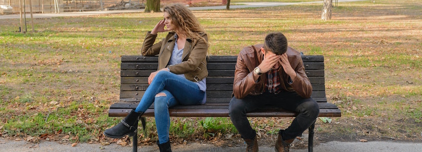 A couple on a bench looking sad and separated