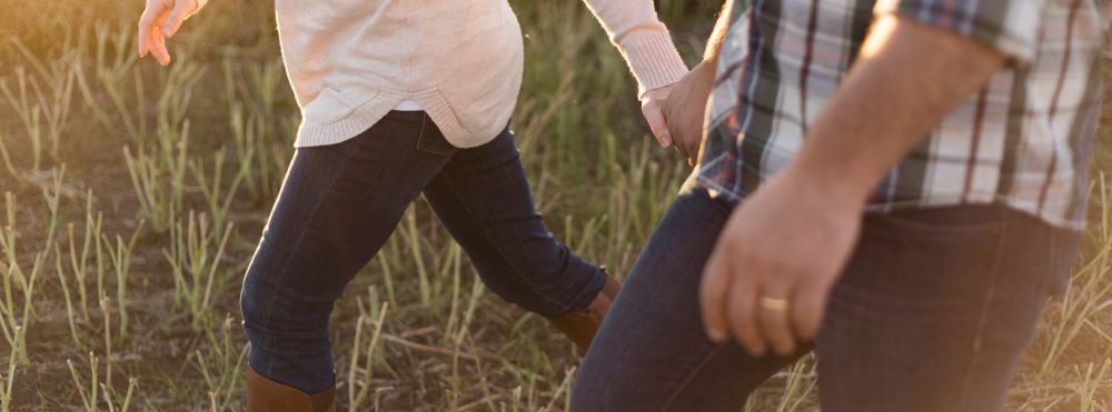 Couple holding hands in tall grass - family law