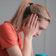 Young woman holding head in hands looking at computer