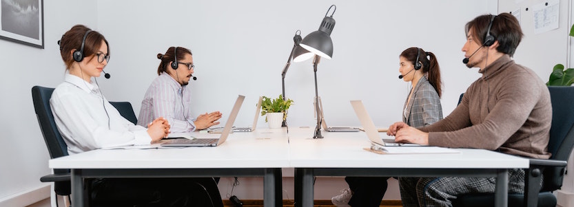 Four office staff on support calls with headsets