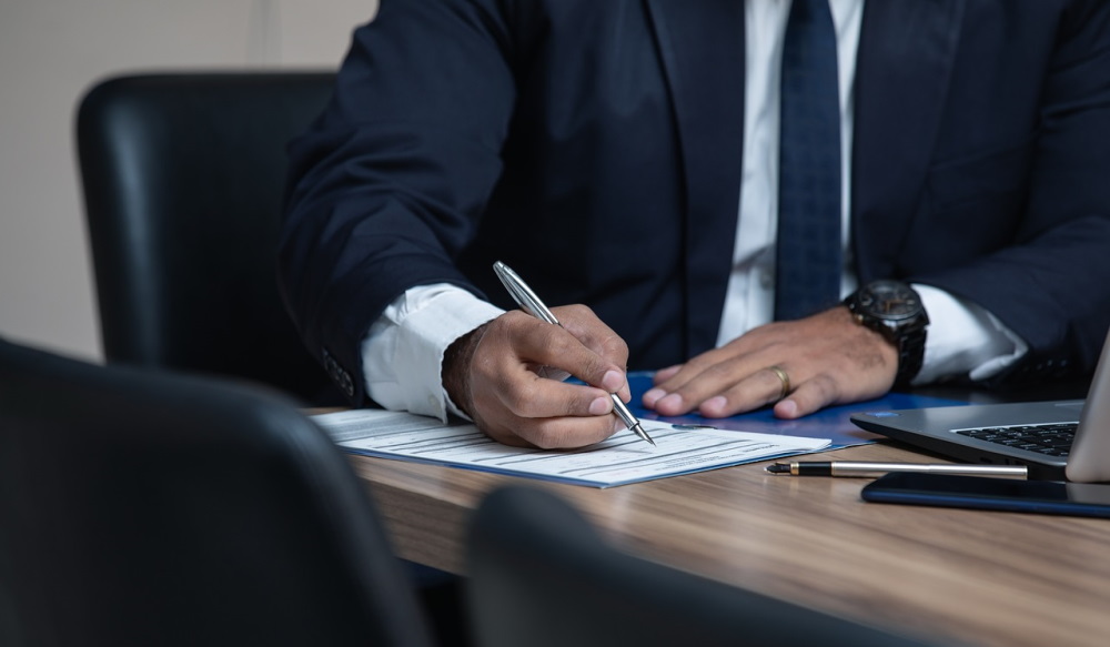 man in suit signing paperwork